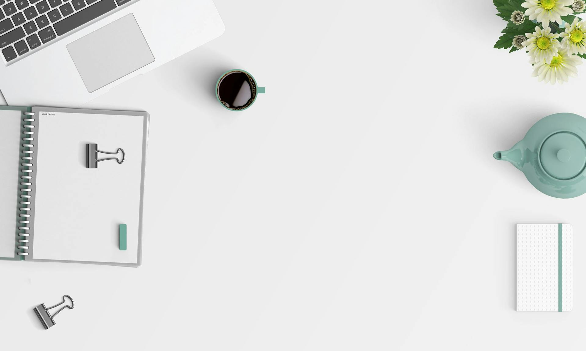 Ein sehr ordentlicher Schreibtisch von oben fotografiert. Darauf stehen, ein Laptop, eine Tasse, ein Notizheft, eine Blume und andere kleine Bürogegenstände
